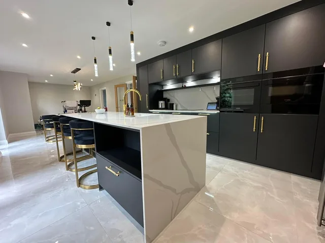 Pendant lights and recessed downlights in a kitchen with a marble island