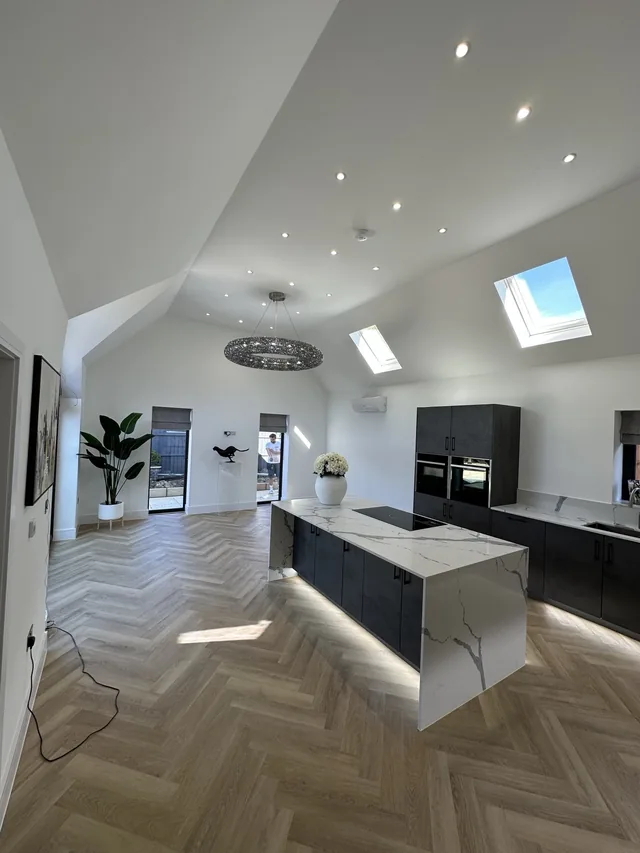Recessed downlights, a circular pendant and illuminated island in a vaulted kitchen